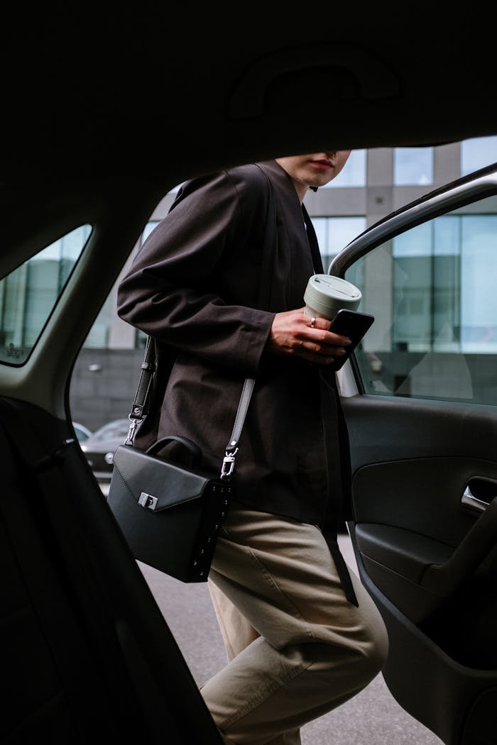 hero-img-02 Stylish woman entering a car, holding coffee and smartphone, showcasing urban lifestyle.